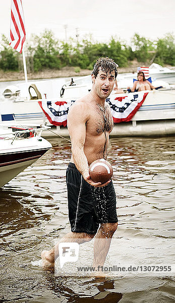Portrait of man holding football while walking in water