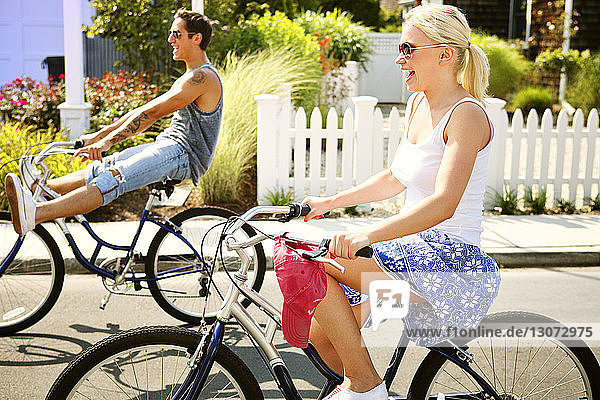 Happy couple riding bicycle on street