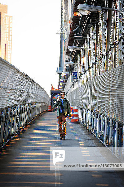 Mann schaut weg  während er auf dem Fußgängerweg der Manhattan Bridge geht