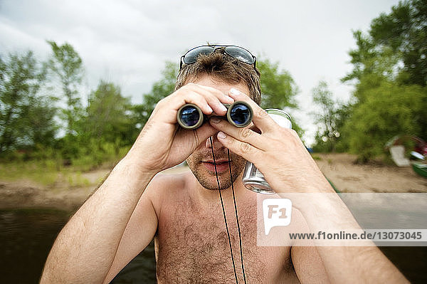 Man holding binoculars while standing in sea