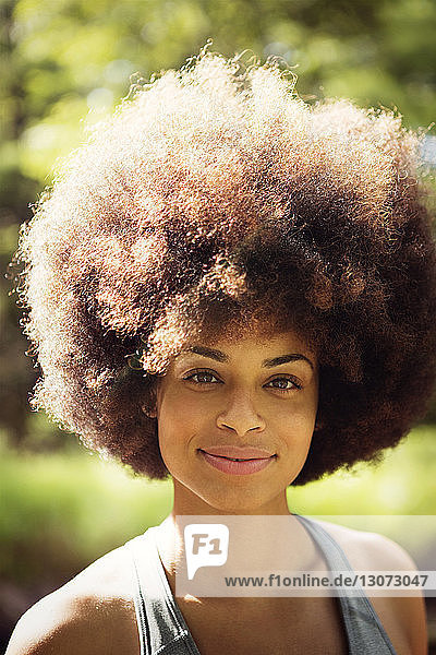 Close-up portrait of smiling woman with frizzy hair in forest