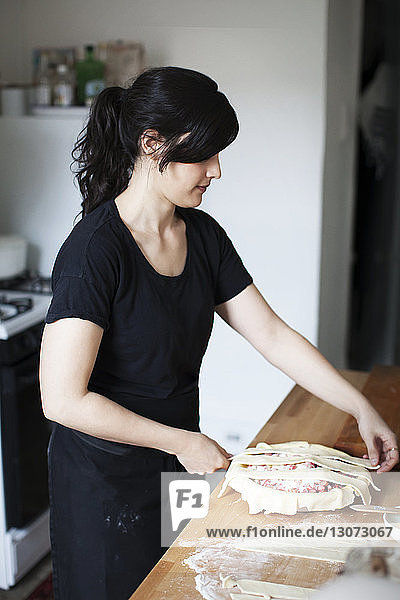 Frau bereitet Rhabarberkuchen zu  während sie an der Küchentheke steht