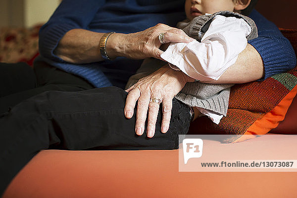 Mitschnitt der Großmutter  die den Jungen umarmt  während sie sich zu Hause auf dem Sofa entspannt