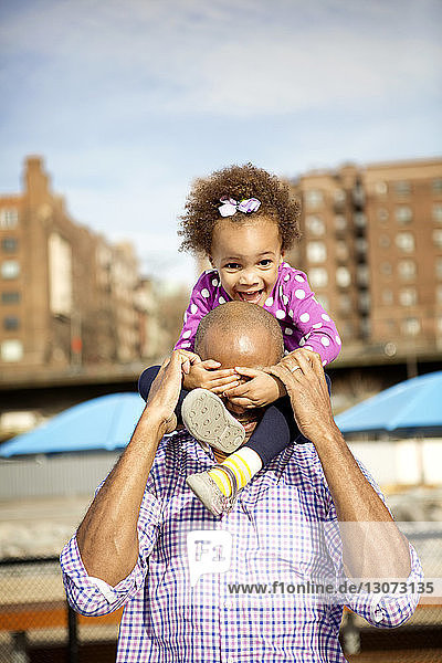 Playful father and daughter standing against buildings in city