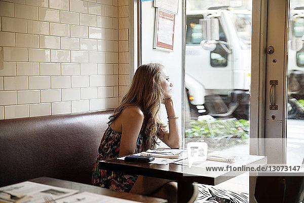 Side view of thoughtful woman looking away while sitting in restaurant
