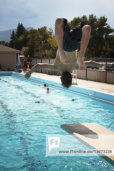 Rear view of teenage boy jumping in swimming pool