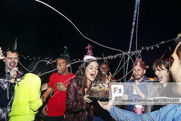Glückliche Freunde genießen mit Geburtstagskuchen in nächtlicher Party