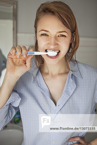 Porträt einer Frau beim Zähneputzen im Stehen zu Hause