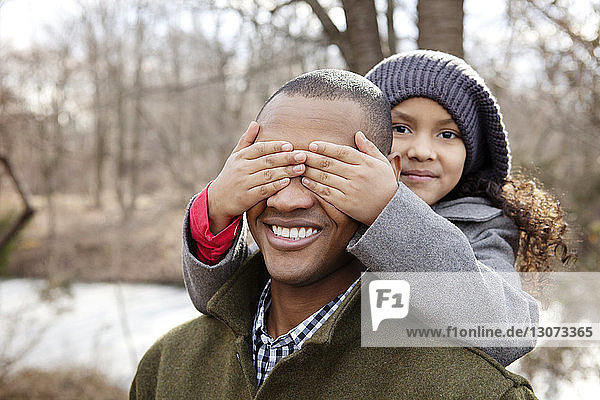 Portrait of girl covering father's eyes