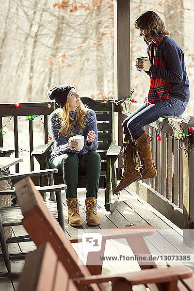 Freunde  die auf der Veranda sitzend einen Drink genießen