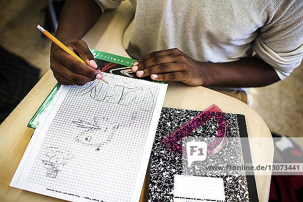Hochwinkelansicht eines Teenagers  der im Klassenzimmer auf Millimeterpapier zeichnet