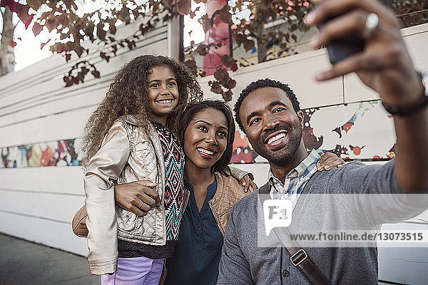 Family taking selfie on mobile phone at sidewalk