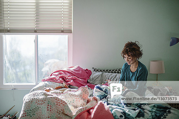 Lächelndes Mädchen spielt Videospiel  während es zu Hause auf dem Bett sitzt