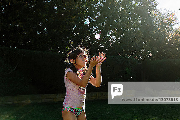 Mädchen spielt mit Wasserbombe im Garten