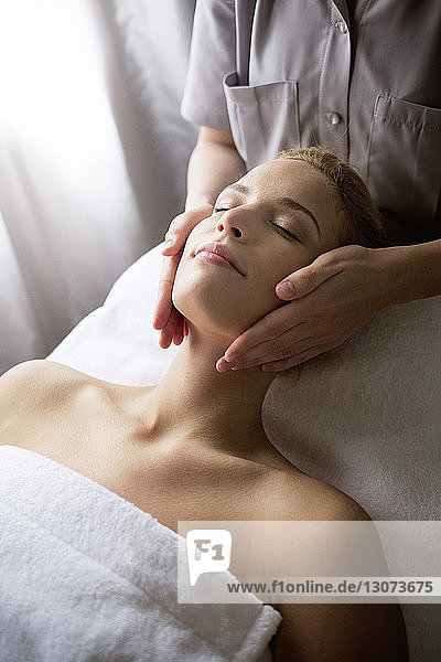 Female therapist massaging woman's face at spa