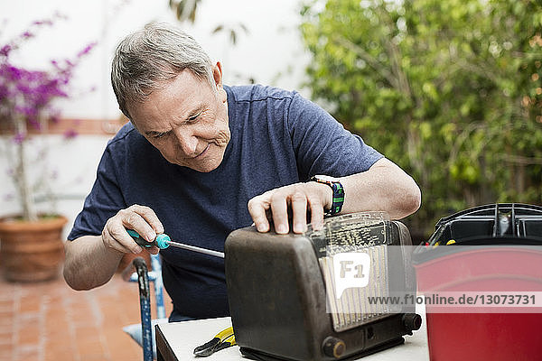 Leitender Mann repariert altmodisches Radio auf dem Hof