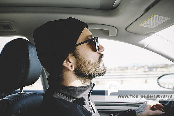 Side view of man wearing knit hat while driving car