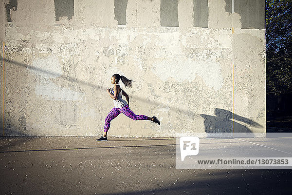 Frau joggt auf der Straße an der Mauer