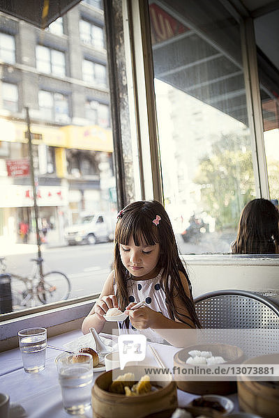 Mädchen schaut Knödel im Löffel an  während sie im Restaurant sitzt