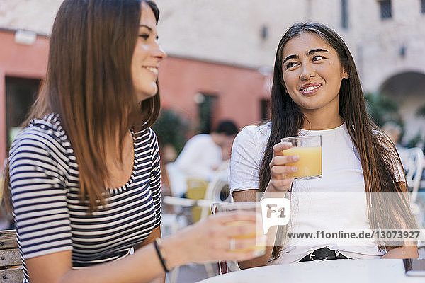 Freunde mit Getränken unterhalten sich am Tisch im Straßencafé