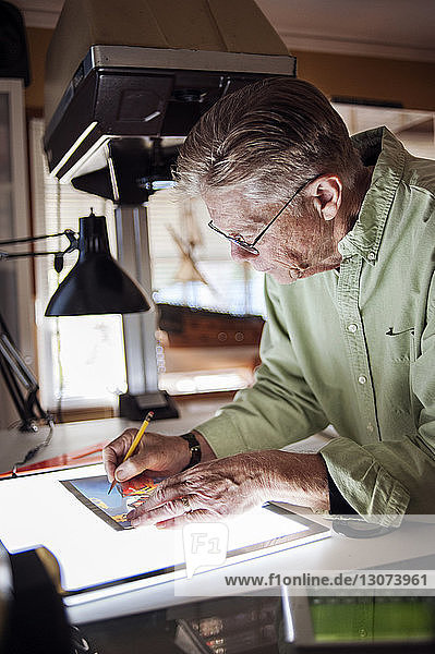 Älterer Mann zeichnet zu Hause auf Grafiktablett