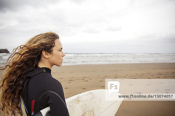 Seitenansicht einer Frau mit Surfbrett am Strand