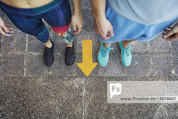High angle view of man and woman standing by arrow symbol on floor