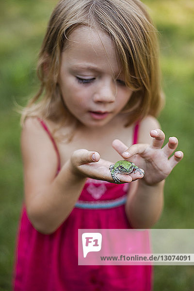 Cute girl playing with frog in yard