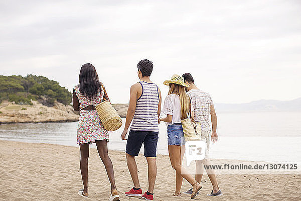 Rückansicht von multi-ethnischen Freunden  die am Strand spazieren gehen