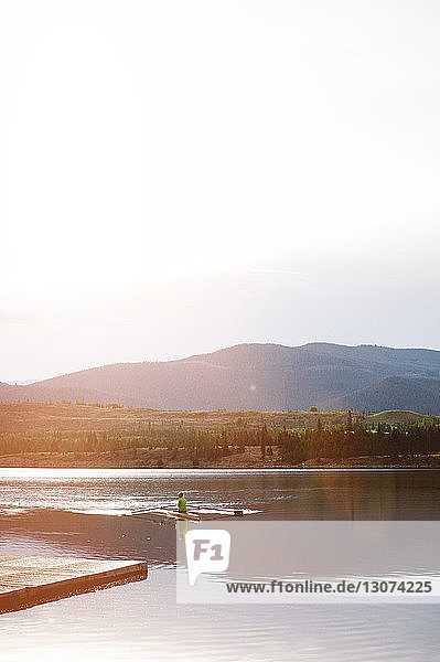 Hochwinkelaufnahme einer Kajakfahrerin auf einem See bei klarem Himmel