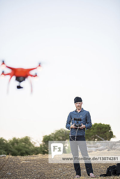 Mann in voller Länge bedient Drohne durch Fernsteuerung gegen freien Himmel