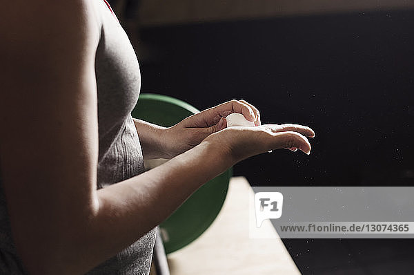 Seitenansicht einer Athletin  die ihre Hände im Fitnessstudio mit Kreide einstreicht