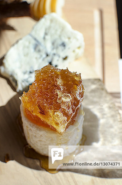 Hochwinkelansicht von Honig mit Käse auf Holztisch