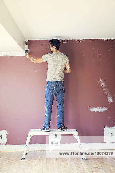 Rückansicht eines Mannes  der zu Hause eine Wand malt