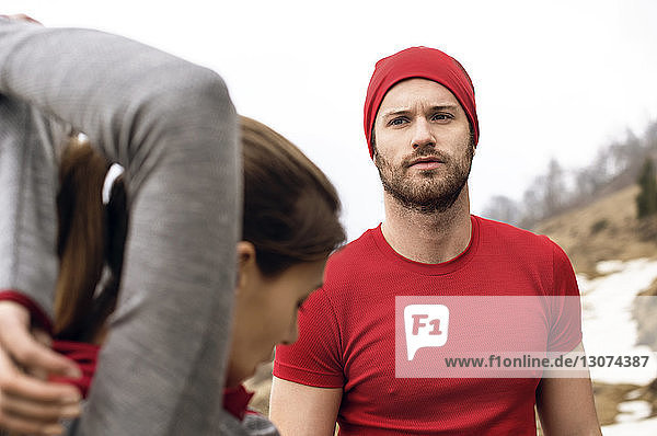 Man looking at woman exercising on mountain during winter