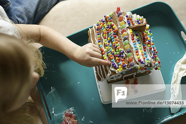 Hochwinkelansicht eines Mädchens  das zu Hause sein Spielzeughaus dekoriert