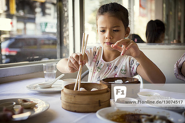 Girl taking dumplings while sitting in restaurant