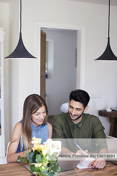 Happy young couple using laptop at home