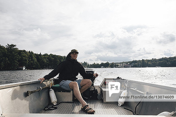Man riding motorboat on Lake Rosseau against cloudy sky