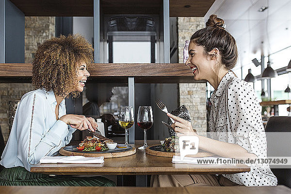 Cheerful businesswomen having lunch at table in restaurant