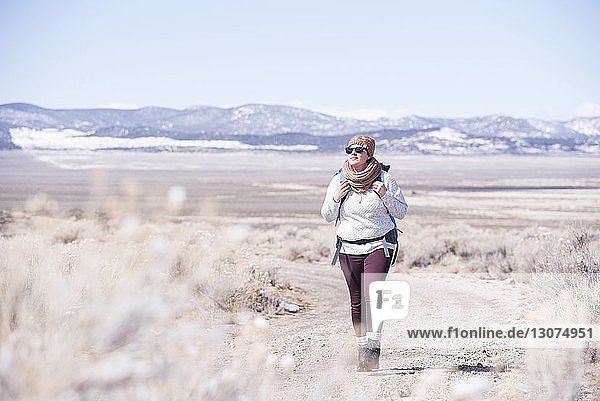 Full length of female hiker exploring desert against sky during winter