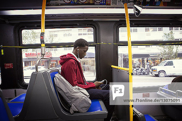 Side view of student listening music while traveling in bus