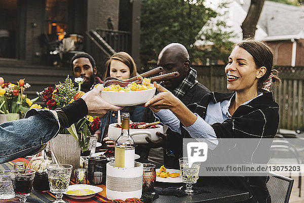 Friends enjoying food while sitting at table in backyard