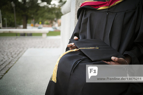 Mid-section of woman holding mortarboard