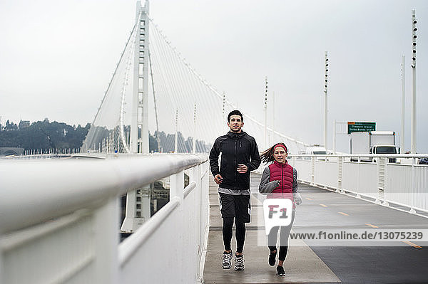 Porträt von entschlossenen Athleten  die auf der Bay Bridge gegen den Himmel laufen
