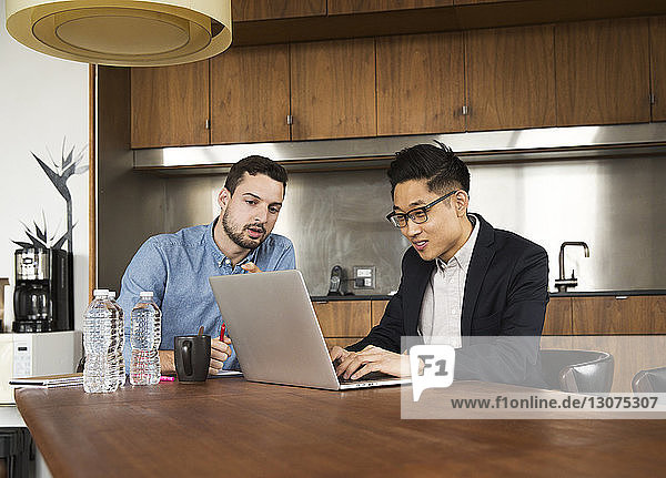 Business partners talking over laptop computer at creative office