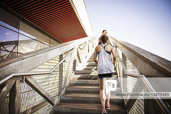 Rückansicht von Frauen  die auf Stufen und Treppen gegen den klaren Himmel gehen