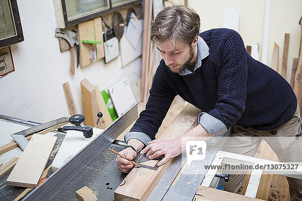 Schreiner beim Vermessen von Holzbohlen in der Werkstatt