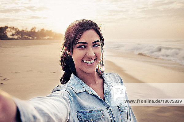 Junge Frau am Strand beim Selfie