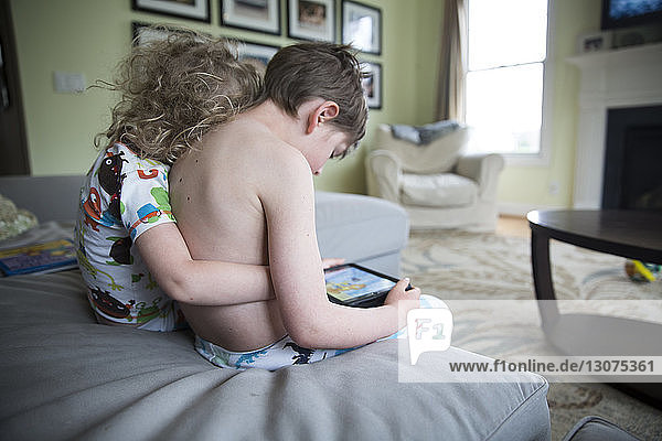 Girl embracing brother using tablet computer on sofa at home